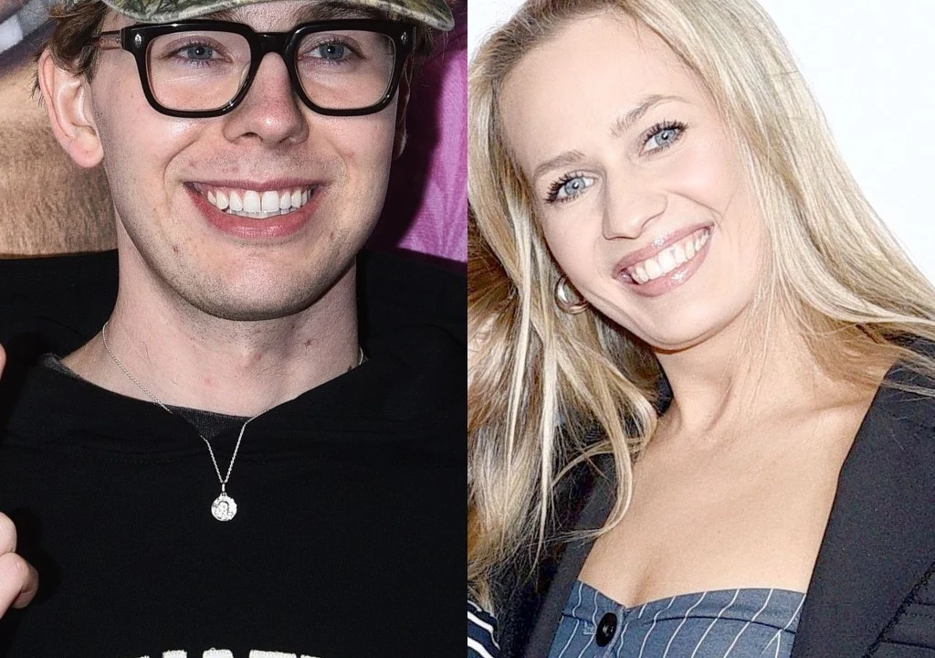 Dwie uśmiechnięte osoby, mężczyzna w okularach i czapce oraz kobieta z długimi blond włosami, pozują razem.