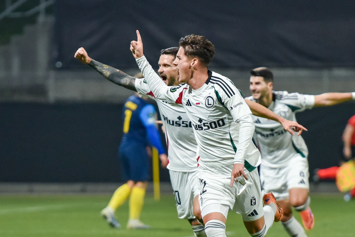 Jeśli Legia wygra dziś ze Spartą Praga, to zwiększy szansę Polski na doścignięcie Czech w rankingu krajowym UEFA Piłkarze drużyny Legia Warszawa w białych strojach świętują zdobycie gola. Jeden z zawodników biegnie z uniesionym palcem wskazującym, wyrażając radość, a za nim podążają jego koledzy z drużyny. W tle widoczny przeciwnik w niebiesko-żółtym stroju.