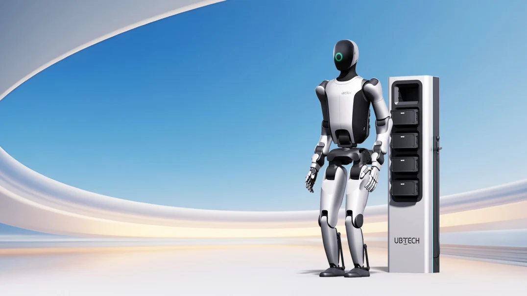 Robot humanoidalny Walker S2 firmy UBTech Robotics. Humanoidalny robot stojący obok pionowego urządzenia służącego prawdopodobnie do ładowania lub komunikacji, całość na tle futurystycznego, jasnego wnętrza z łukami i otwartą przestrzenią.