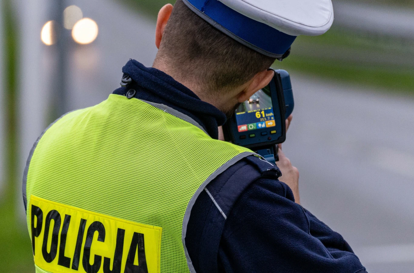 27 listopada ruszyła krajowa operacja "Prędkość". Funkcjonariusz policji w odblaskowej kamizelce mierzy prędkość nadjeżdżających pojazdów przy pomocy ręcznego miernika prędkości, stojąc przy drodze.