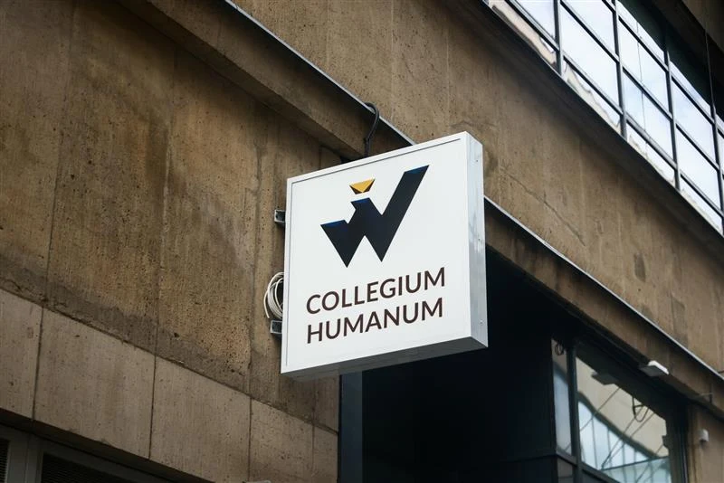 Prokuratura Krajowa poinformowała o pierwszym akcie oskarżenia w sprawie nieprawidłowości w Collegium Humanum Szyld z logotypem i nazwą Collegium Humanum zawieszony na betonowej elewacji budynku, w tle fragment okna i odbicie światła.
