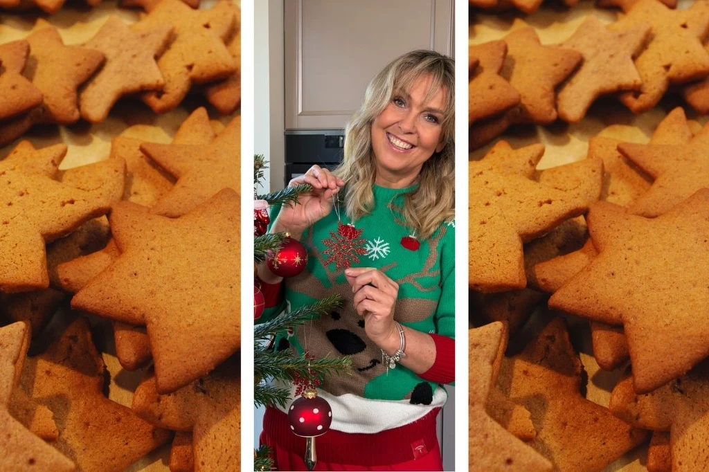 Pierniczki to świąteczny klasyk Uśmiechnięta kobieta w świątecznym swetrze dekoruje choinkę, trzymając ozdobę, na tle dużego zbliżenia na pierniczki w kształcie gwiazdek.