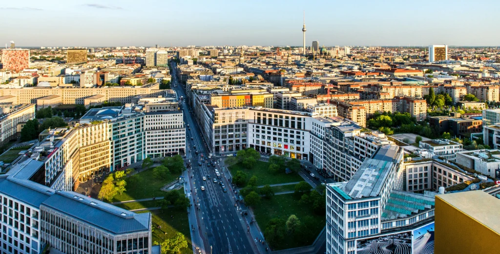 W Berlinie do 2040 r. co 15 metrów ma stać drzewo Panorama dużego miasta z wieżowcami, szeroką główną ulicą biegnącą przez środek kadru i licznymi budynkami biurowymi oraz mieszkalnymi. W tle widoczna charakterystyczna wieża telewizyjna.