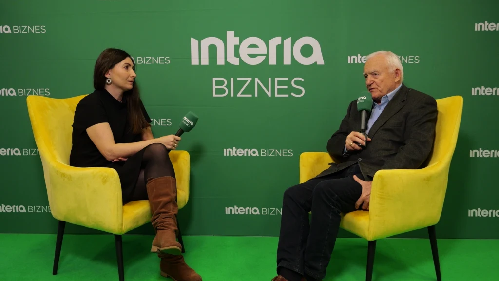 Dwoje ludzi siedzi na żółtych fotelach na tle zielonej ściany z napisem interia BIZNES, prowadzą rozmowę trzymając mikrofony, kobieta i mężczyzna są zaangażowani w wywiad.