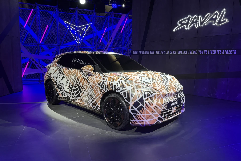 Model zadebiutuje i trafi do sprzedaży już w przyszłym roku Samochód miejski o nowoczesnym designie pokryty kamuflażem z geometrycznym wzorem, stojący na ekspozycji w sztucznie oświetlonym wnętrzu. W tle podświetlone logo producenta i napis Raval.