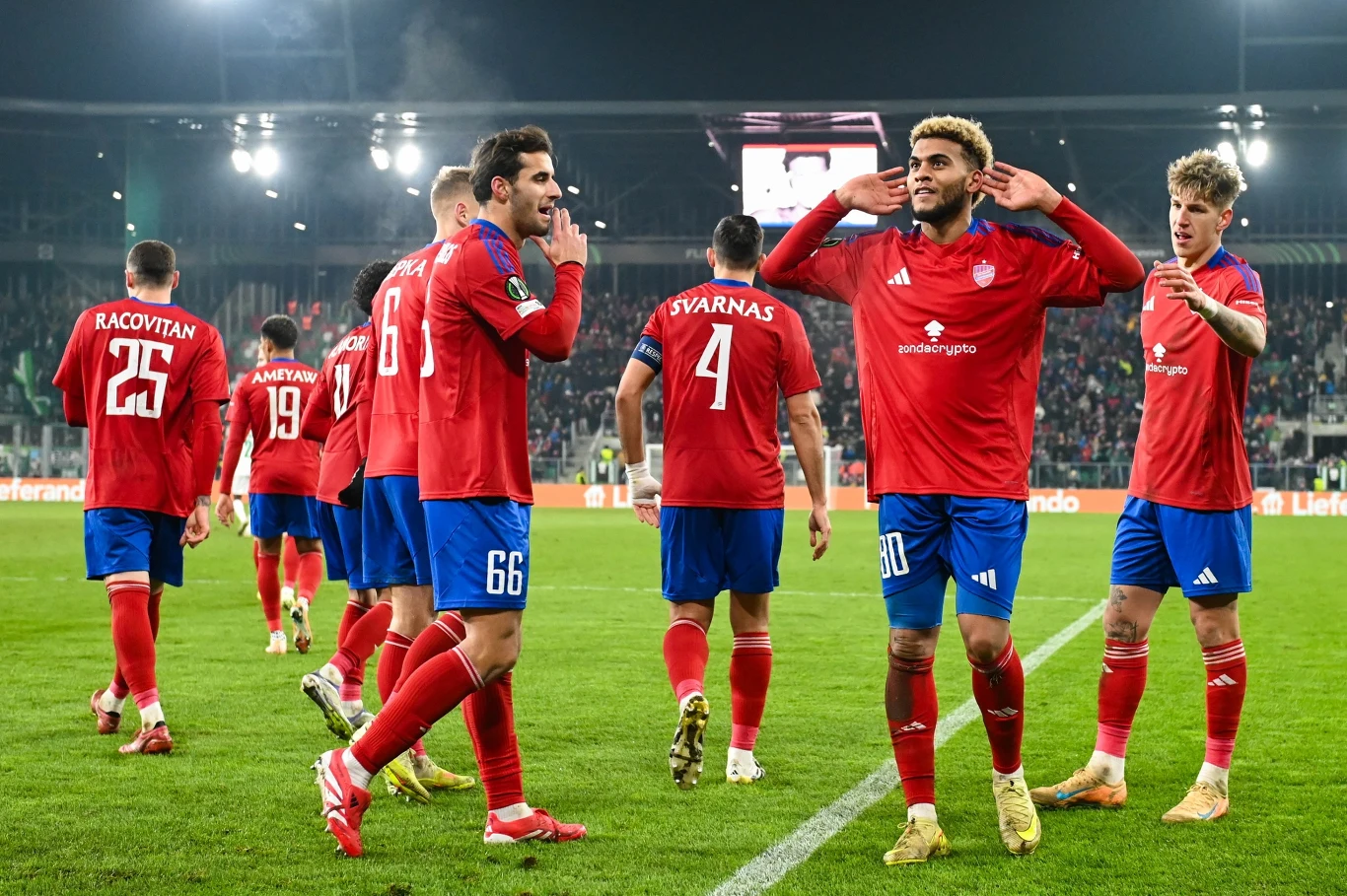 Lamine Diaby-Fadiga z hat-trickiem dla Rakowa Częstochowa w Lidze Konferencji Grupa piłkarzy drużyny w czerwonych koszulkach świętuje na murawie stadionu po zakończonym meczu, w tle widoczni kibice oraz jaskrawe światła stadionowe.