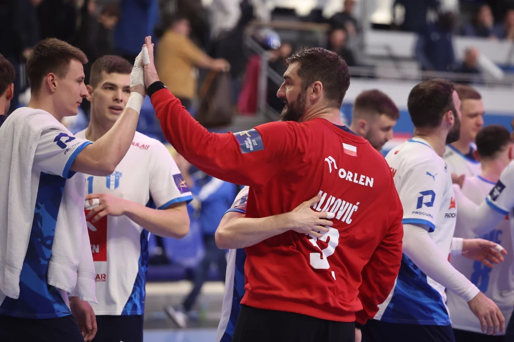 Mirko Alilović zbiera gratulacje w Paryżu Grupa szczypiornistów gratuluje sobie podczas przerwy w meczu, zawodnicy ubrani są w sportowe stroje, wśród nich wyróżnia się bramkarz w czerwonym stroju z napisem Orlen.