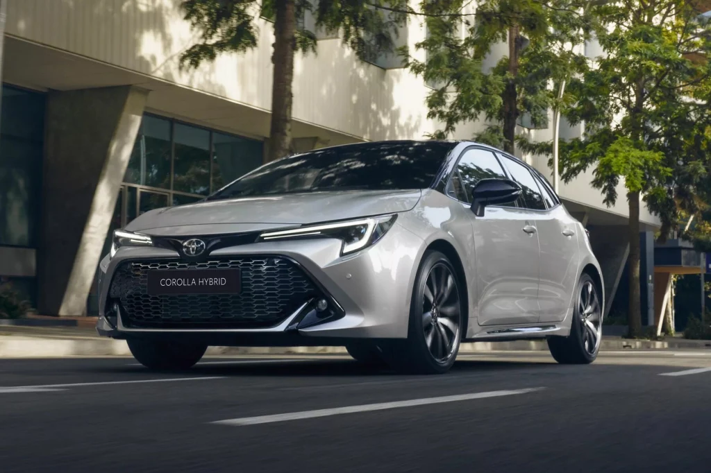 Mechanicy cenią silnik Toyota 1.8 Hybrid za jego prostotę. Jednostka napędza m.in. Corollę Hybrid Srebrny samochód Toyota Corolla Hybrid zaparkowany przy ulicy, nowoczesna sylwetka pojazdu wyróżniająca się na tle budynku i drzew w tle.
