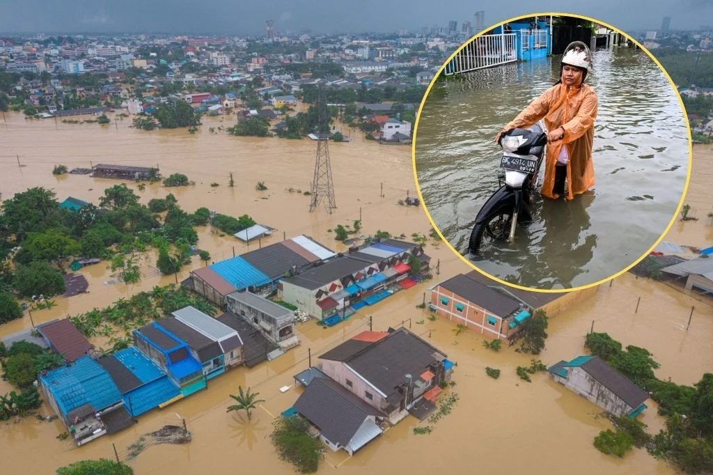 Zalana dzielnica mieszkalna z widocznymi dachami domów otoczonymi wodą, wstawka przedstawia osobę w pelerynie przeciwdeszczowej prowadzącą motocykl przez głęboki nurt wody.