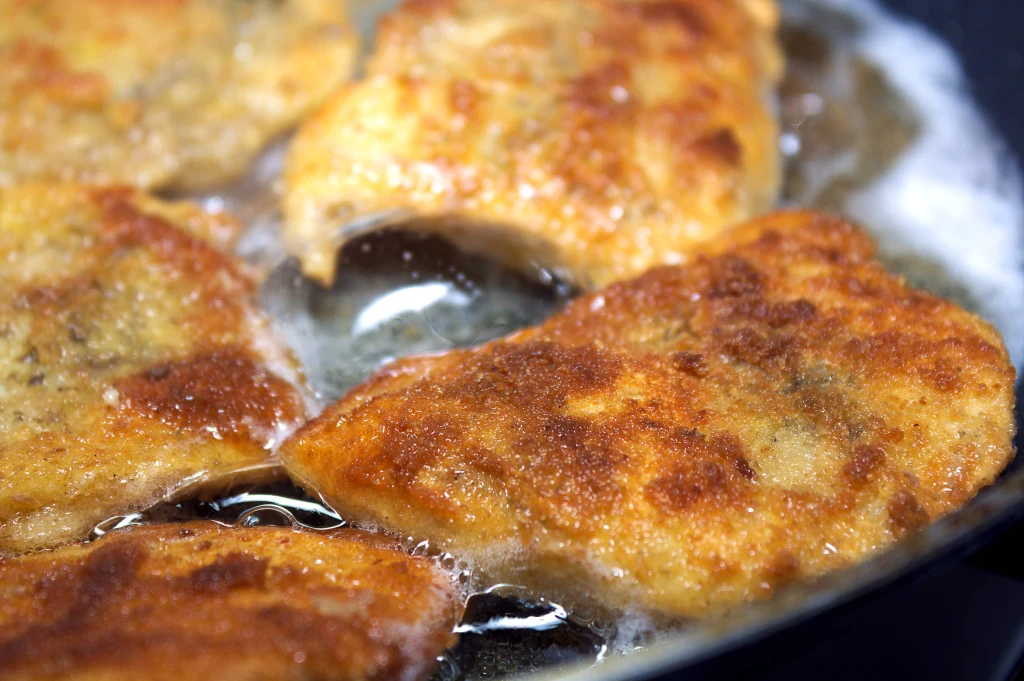 Kawałki ryby w złocistej panierce smażone na głębokim tłuszczu, otoczone pęcherzykami gorącego oleju, uzyskują chrupiącą skórkę.