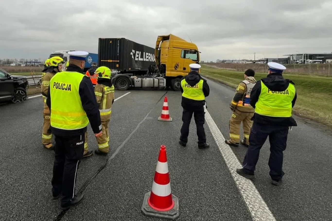 Ciężarówka najpierw uderzyła w barierki, a następnie w osobowego Hyundaia. Do zdarzenia doszło na autostradzie A1 Policjanci i strażacy zabezpieczają miejsce wypadku drogowego na autostradzie, gdzie duża ciężarówka stoi w poprzek jezdni, a pas ruchu jest zablokowany pachołkami.