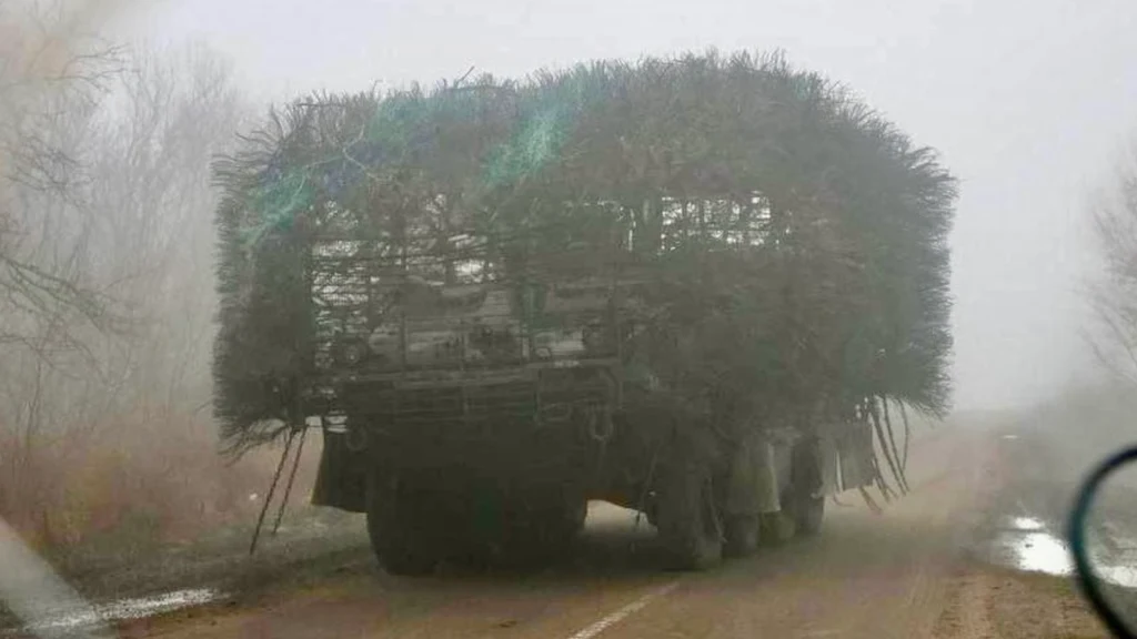 Ukraiński Stryker z zaskakującymi modyfikacjami. Wcześniej się z nich śmiano Ciężarówka ukryta pod warstwą gałęzi jedzie po błotnistej, leśnej drodze w mglistym krajobrazie. Gałęzie maskujące całkowicie zakrywają nadwozie pojazdu, co sugeruje próbę ukrycia go w terenie.