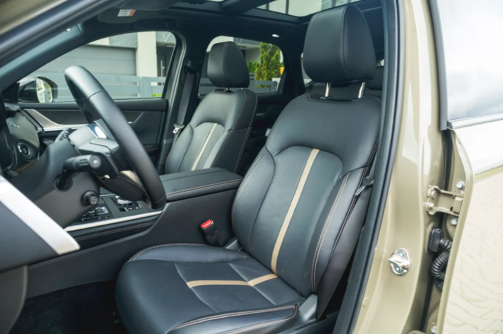 Mazda CX-60 ma wygodne fotele, ale brakuje im podparcia bocznego Wnętrze samochodu z widokiem na przednie fotele, deskę rozdzielczą oraz elementy konsoli środkowej; tapicerka skórzana w dwóch odcieniach z jasnymi wstawkami, przestronne i zadbane miejsce kierowcy oraz pasażera, widoczny nowoczesny panel sterowania.