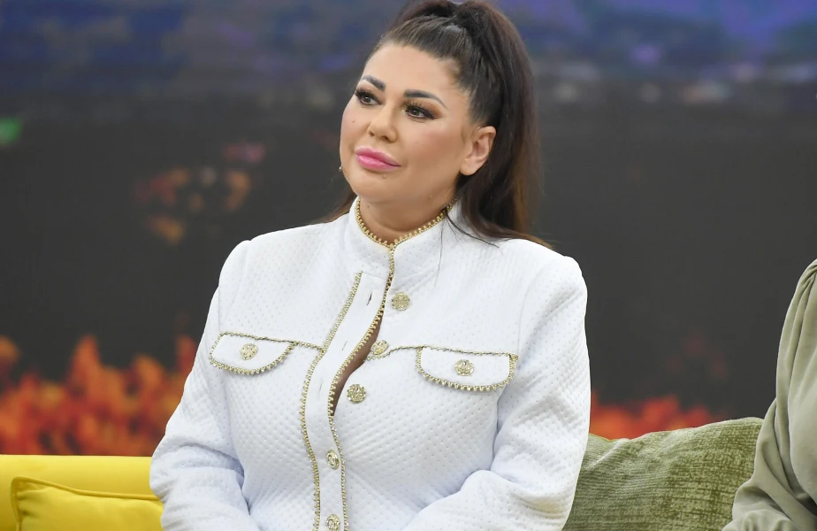 Iwona Węgrowska Iwona Węgrowska w białym żakiecie ze złotymi guzikami siedzi na kanapie.