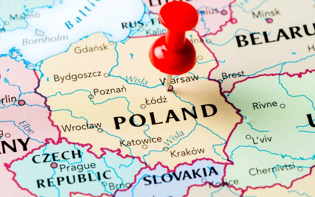 Fragment mapy Europy Środkowej z wyraźnie zaznaczoną Polską, na której widnieje czerwona pinezka wskazująca miejsce Warszawy, otoczonej przez pozostałe państwa regionu.