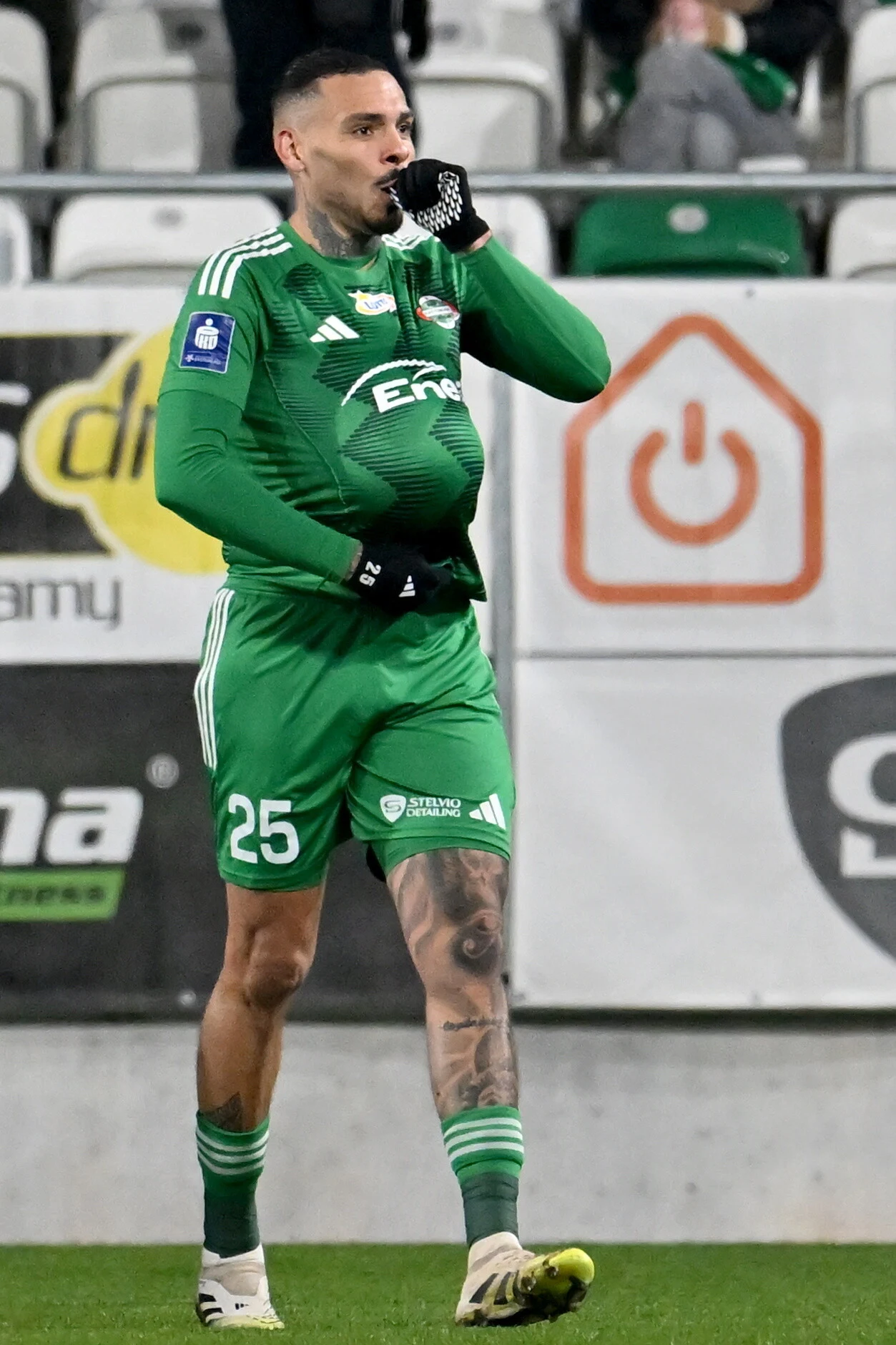 Po zdobyciu bramki Maurides wysłał światu radosny komunikat Piłkarz w zielonym stroju świętuje zdobycie gola, wykonując gest pocałowania dłoni i wkładania piłki pod koszulkę, co sugeruje dedykację bramki oraz nawiązanie do motywu ciąży. W tle widoczne trybuny oraz reklamy.