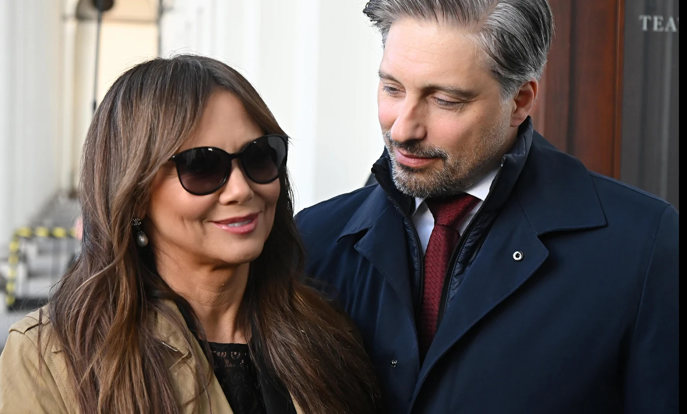 Kinga Rusin i Marek Kujawa Para dorosłych ludzi uchwycona podczas rozmowy na zewnątrz, kobieta w okularach przeciwsłonecznych uśmiecha się, mężczyzna spogląda na nią z uprzejmością, oboje ubrani elegancko.