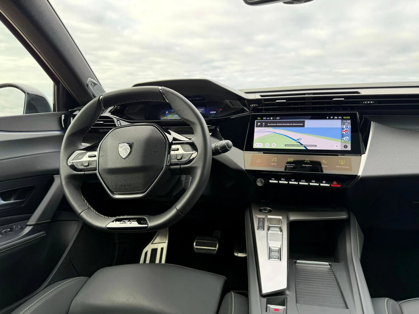 Nowoczesne wnętrze samochodu z cyfrowym kokpitem, kierownicą wielofunkcyjną, dużym ekranem dotykowym z nawigacją oraz konsolą środkową z przyciskami i dźwignią zmiany biegów