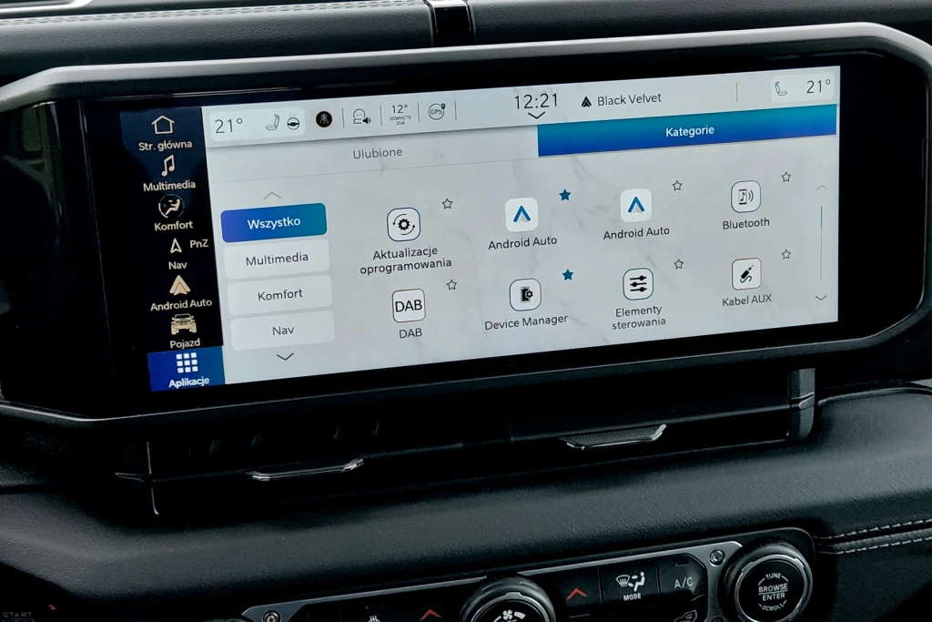 Centralny ekran ma aż 12,3 cala Duży ekran dotykowy systemu multimedialnego w samochodzie z wyświetlonym menu głównym, na którym widoczne są ikony różnych funkcji, takich jak Android Auto, Bluetooth, DAB, komfort czy ustawienia systemowe. Poniżej panel sterowania klimatyzacją.