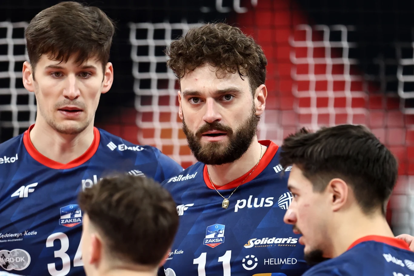 Kamil Rychlicki i jego ZAKSA Kędzierzyn-Koźle zaskoczyła Indykpol AZS Olsztyn w dwóch pierwszych setach Czterech siatkarzy zespołu Grupa Azoty ZAKSA Kędzierzyn-Koźle w granatowych strojach drużynowych podczas rozmowy na boisku, w tle fragment siatki i trybun.