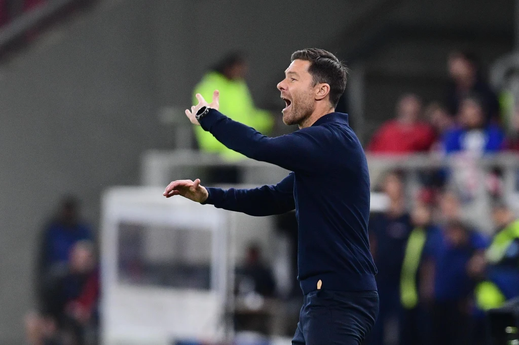 Xabi Alosno, trener Realu Madryt Mężczyzna w ciemnym stroju gestykuluje energicznie podczas wydarzenia sportowego na stadionie, w tle rozmyta widownia oraz kilku pracowników ochrony.