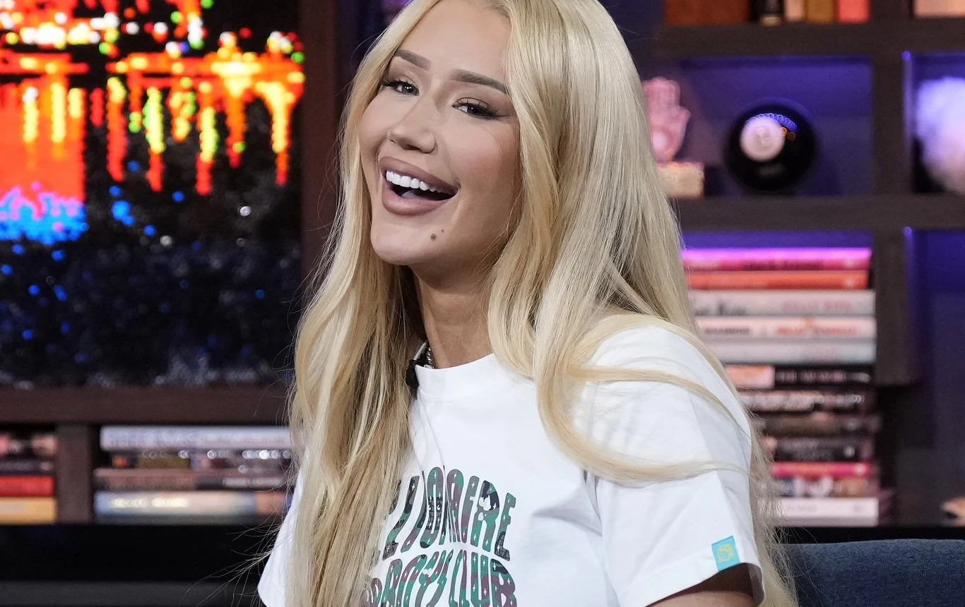 Iggy Azaela jasno wyraziła swoje zdanie o powrocie do muzyki Młoda kobieta z długimi blond włosami uśmiecha się szeroko, ma na sobie jasny t-shirt, w tle znajduje się półka z książkami oraz kolorowe światła odbijające się w ciemnej powierzchni.