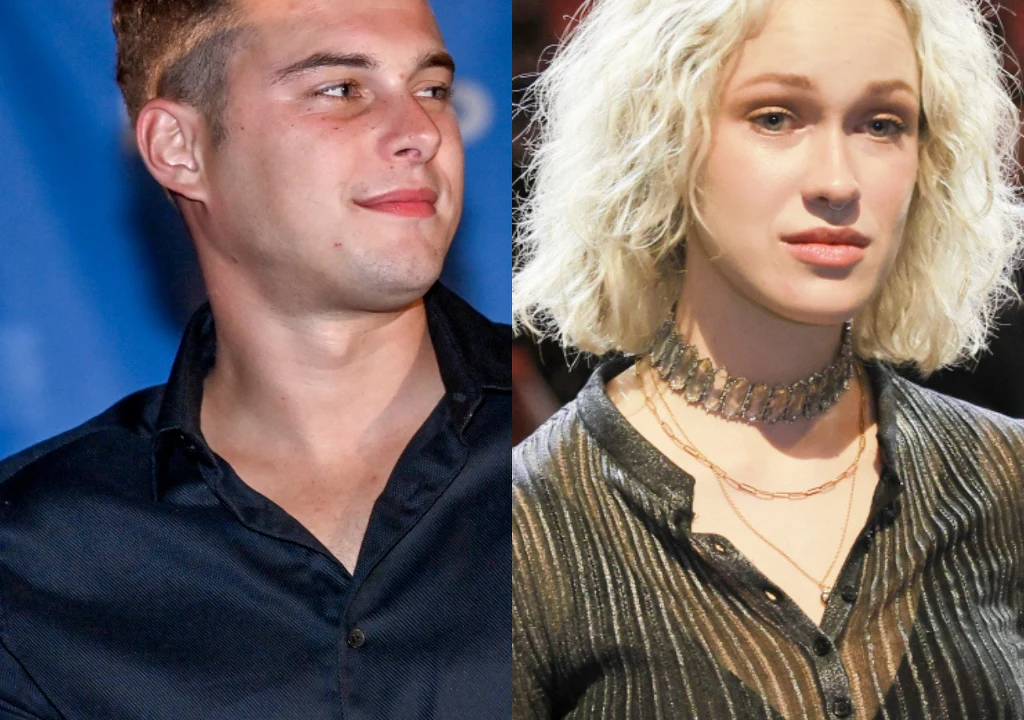 Dwie osoby, jedna z krótkimi, ciemnymi włosami ubrana w ciemną koszulę, druga z jasnymi, kręconymi włosami, nosząca czarną, błyszczącą bluzkę i naszyjnik. Obie patrzą w różne strony, tło rozmyte.