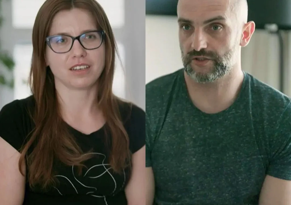 Katarzyna Zawidzka i Maciej Walkowiak, "Ślub od pierwszego wejrzenia" Kobieta w okularach oraz mężczyzna z brodą siedzą w pomieszczeniu, oboje patrzą przed siebie, wyglądają na zamyślonych lub zaangażowanych w rozmowę.