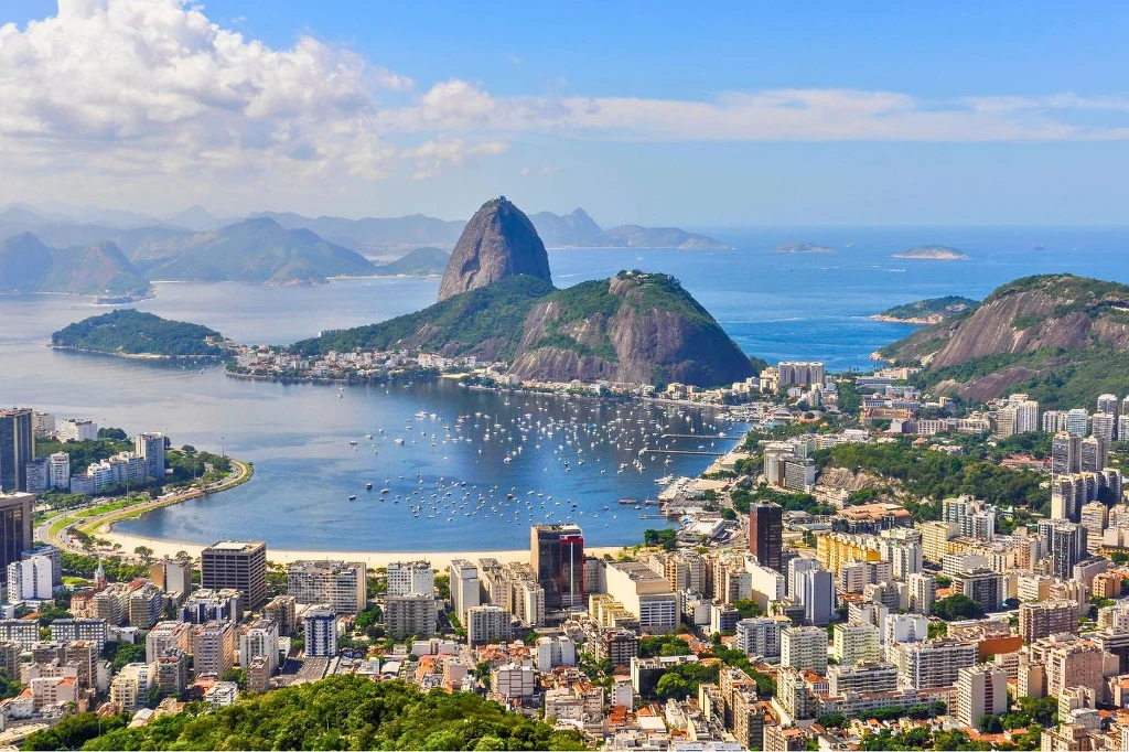 Ten kierunek może okazać się hitem 2026 roku Widok na dużą metropolię położoną nad zatoką, z charakterystyczną górą Pão de Açúcar na pierwszym planie, liczną zabudową miejską, plażą i jachtami na wodzie, w tle widać wzgórza i błękitne morze.