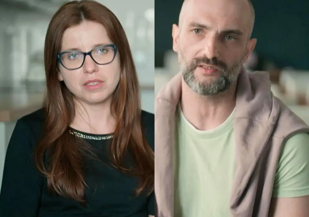 Dwie osoby dorosłe, kobieta w okularach o długich, rudych włosach oraz mężczyzna z brodą i ogoloną głową, siedzą w pomieszczeniu o neutralnym tle, patrząc w stronę aparatu.