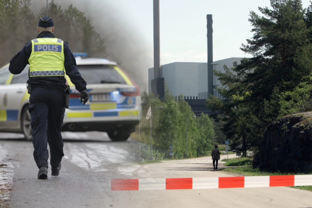 Polacy są oskarżeni o fotografowanie elektrowni jądrowej w Oskarshamn Policjant idzie w stronę radiowozu, w tle widoczna fabryka lub elektrownia otoczona zielenią i czerwono-białą przeszkodą blokującą drogę. Przed budynkiem spaceruje samotna osoba.