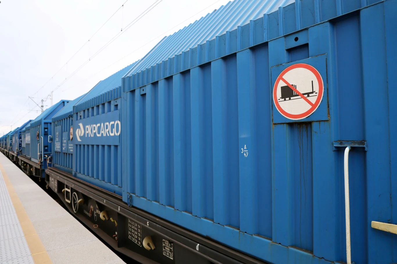 PKP Cargo pozostaje w restrukturyzacji Niebieskie kontenery towarowe PKP CARGO stojące na peronie kolejowym, widoczny znak zakazu wsiadania na wagony.