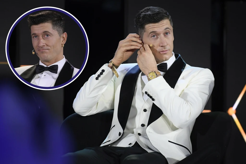 Robert Lewandowski na gali Globe Soccer Awards w Dubaju Mężczyzna w białym smokingu z czarnymi klapami siedzi na scenie i zakłada mikrofon na ucho, w tle scena oświetlona, w lewym górnym rogu znajduje się powiększone okrągłe zbliżenie tej samej osoby.