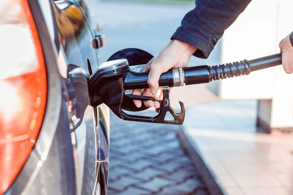 Wielu z nas tankuje pod korek, aby móc przejechać więcej km bez wracania na stację. Okazuje się jednak, że nasze samochody nie lubią tego nawyku Ręka trzymająca pistolet do tankowania, który jest wkładany do wlewu paliwa samochodu na stacji benzynowej.