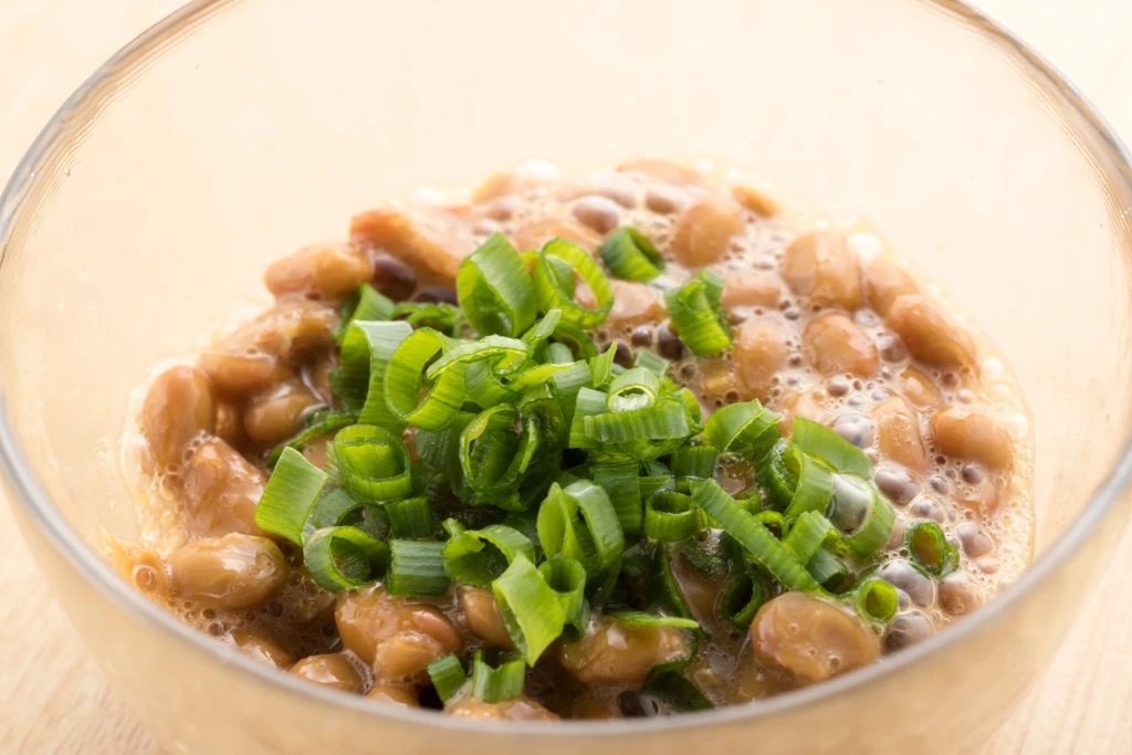 Natto to tradycyjna japońska potrawa z fermentowanej soi, która może skutecznie cofać zmiany miażdżycowe Miska sfermentowanych ziaren soi natto z posiekanym szczypiorem na wierzchu.