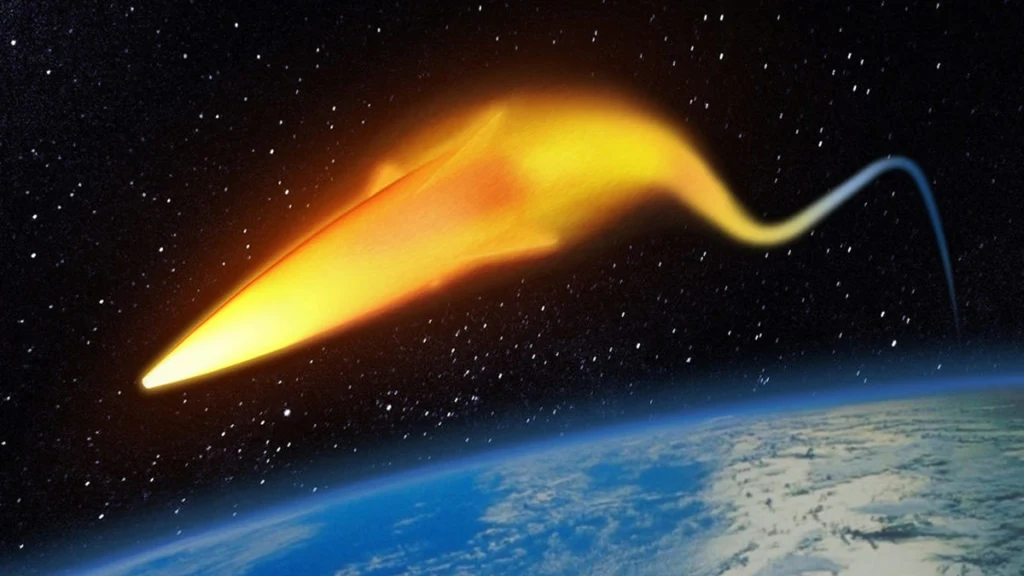 Jasny obiekt przypominający pocisk przelatujący przez atmosferę Ziemi, otoczony świetlistą poświatą, na tle czarnego kosmosu usianego gwiazdami; na dole widoczna zakrzywiona powierzchnia Ziemi.