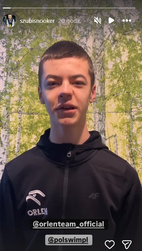 Michał Szubarczyk nadał specjalny komunikat Młody chłopak w czarnej sportowej kurtce z logotypami Orlen i 4F stoi na tle fototapety przedstawiającej brzozy i zielone liście.