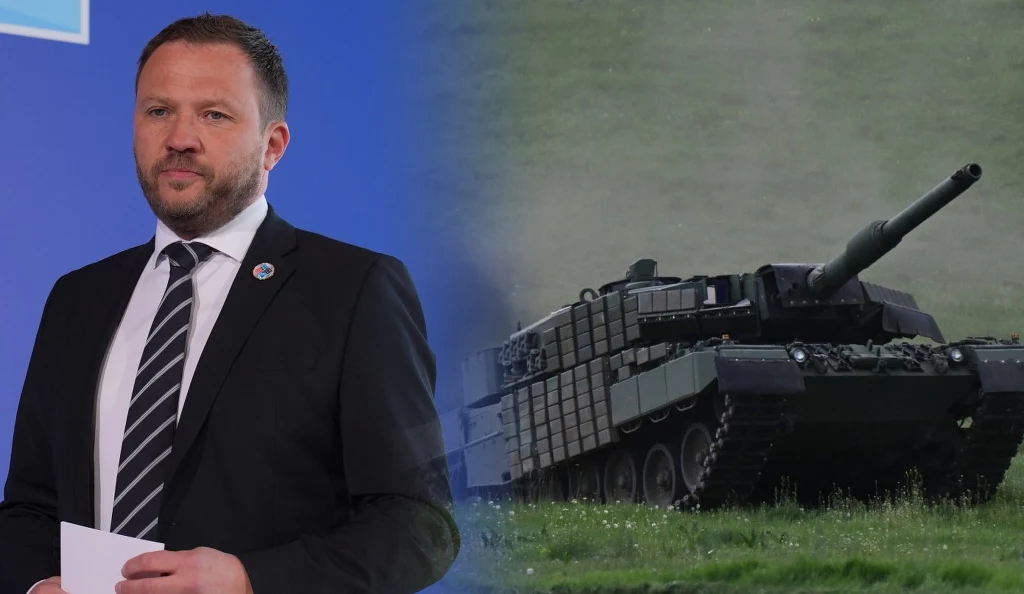 Margus Tsahkna: Estonia wyśle wojska na Ukrainę. Stawia jednak warunek Mężczyzna w garniturze ze złotym odznaczeniem na marynarce trzyma kartki w dłoniach, obok niego nowoczesny czołg bojowy na zielonej trawie. Tło jest rozmyte, podkreślając kontrast między postacią a pojazdem militarnym.