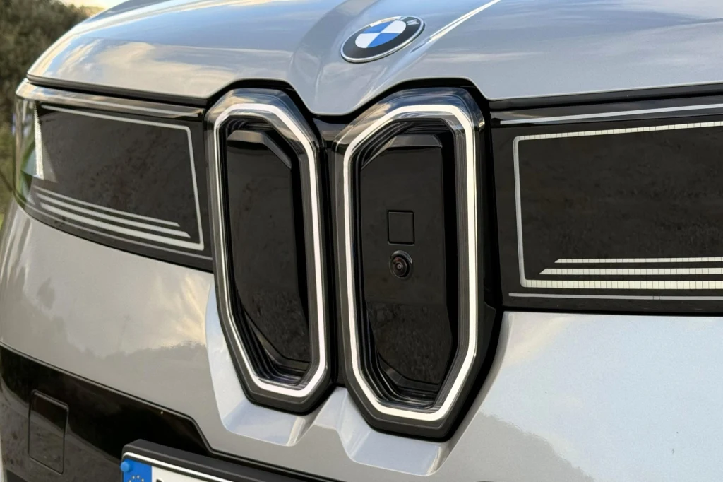 Atrapa chłodnicy w kształcie nerek została pozbawiona chromu. Zastąpiło go oświetlenie. Duża, chromowana atrapa chłodnicy charakterystyczna dla marki BMW, widoczna na srebrnej masce samochodu z wyraźnym logo producenta umieszczonym centralnie powyżej grilla.