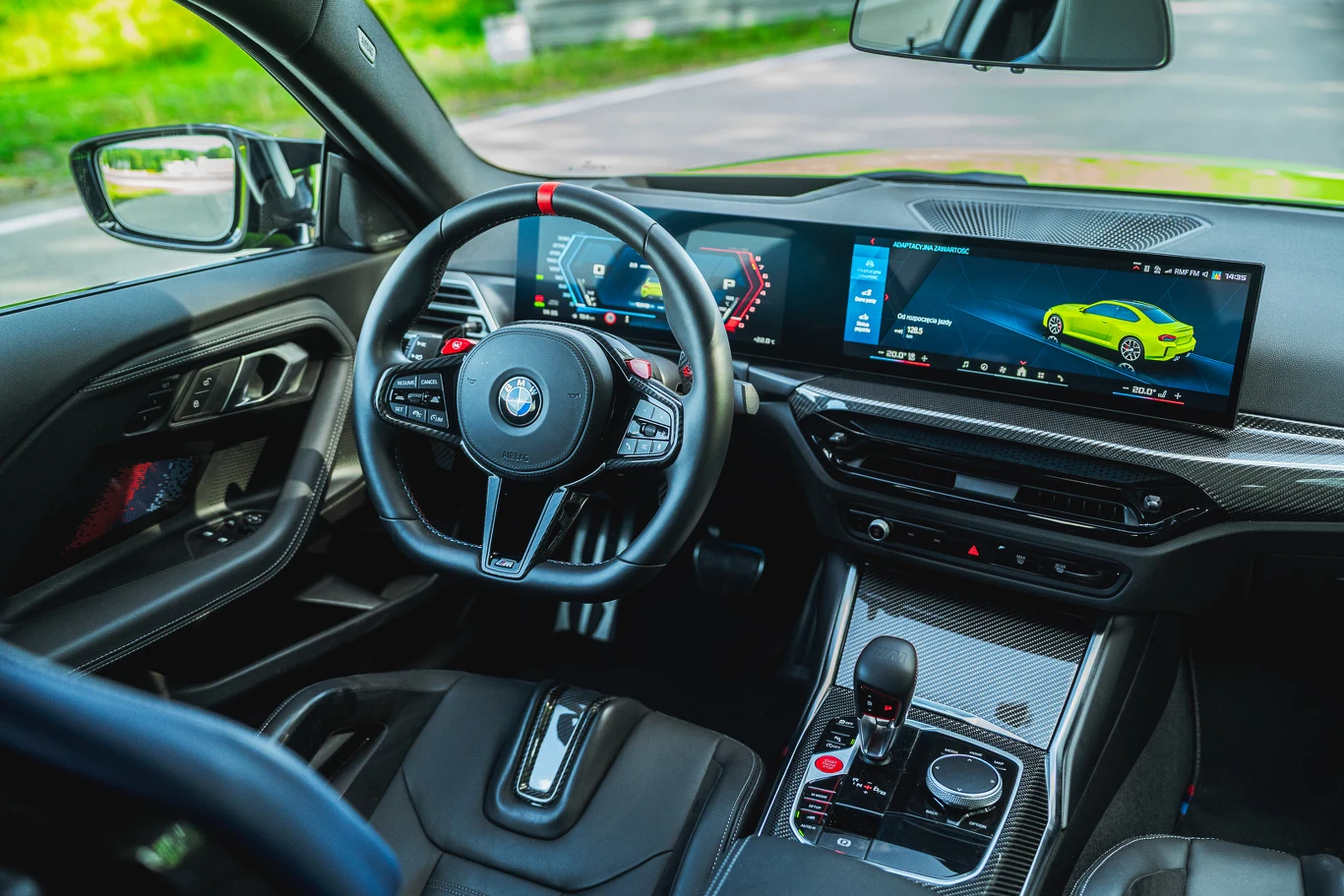 BMW M2 ma deskę dobrze znaną z wielu innych modeli marki. Pod wspólną taflą szkła ukryto ekrany o przekątnej 12,3 oraz 14,9 cala Nowoczesne wnętrze samochodu BMW z cyfrowym zestawem wskaźników, dużym ekranem systemu multimedialnego, sportową kierownicą, elementami wykończenia z włókna węglowego i ergonomicznym układem konsoli środkowej.