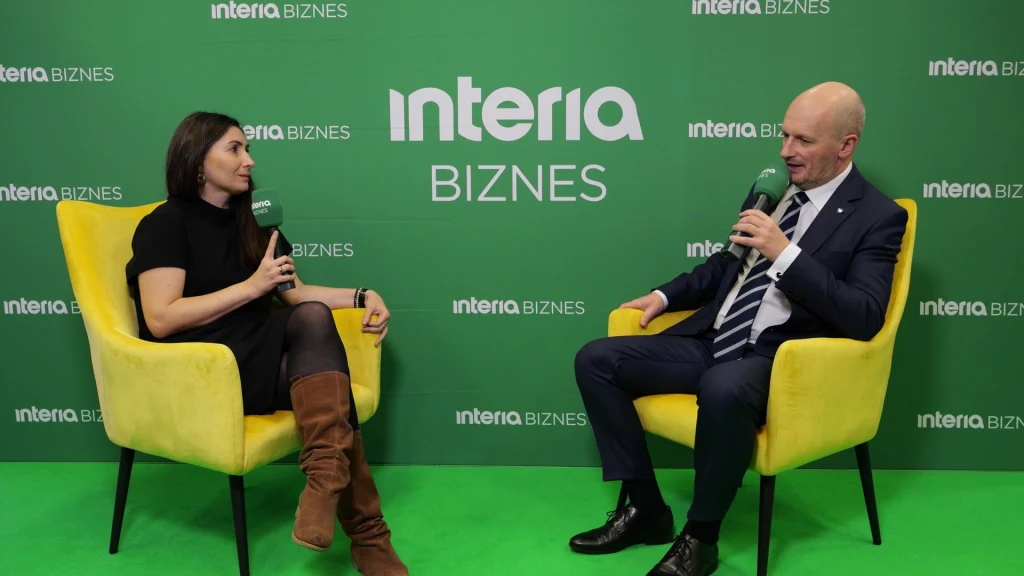 Grupa WB to jedna z firm z polskiego sektora obronnego, które mogą skorzystać na unijnym mechanizmie pożyczek na obronność SAFE Kobieta i mężczyzna siedzą w żółtych fotelach na tle zielonej ścianki z napisem 'interia BIZNES', prowadząc rozmowę z mikrofonami w rękach.