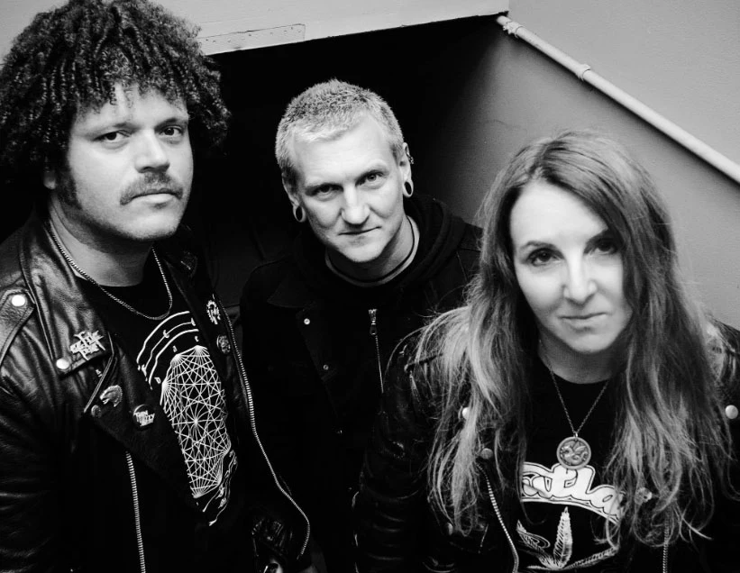 Acid King przyjedzie do Polski w 2026 r. Trzech dorosłych w skórzanych kurtkach pozuje razem na schodach, patrząc bezpośrednio w obiektyw, ich wyraz twarzy sugeruje pewność siebie i lekki uśmiech.