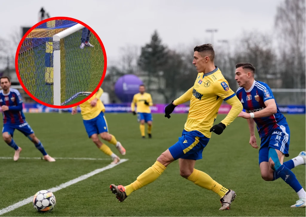 Piłkarz w żółtej koszulce strzela piłkę w stronę bramki podczas meczu piłki nożnej na zielonym boisku. Inni zawodnicy w niebieskich strojach próbują go zatrzymać. W prawym górnym rogu znajduje się powiększone ujęcie piłki wpadającej do bramki.