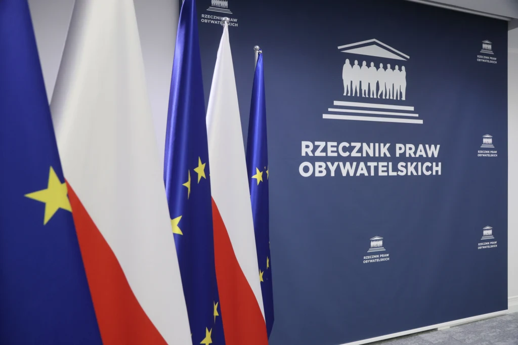 Kancelarie odszkodowawcze w Polsce wciąż bez kompleksowych regulacji, RPO ponownie pyta Ministerstwo Sprawiedliwości Sztandar Rzecznika Praw Obywatelskich wraz z flagami Polski i Unii Europejskiej, ustawionymi obok siebie na tle niebieskiej ściany z oficjalnym logotypem i napisem Rzecznik Praw Obywatelskich.