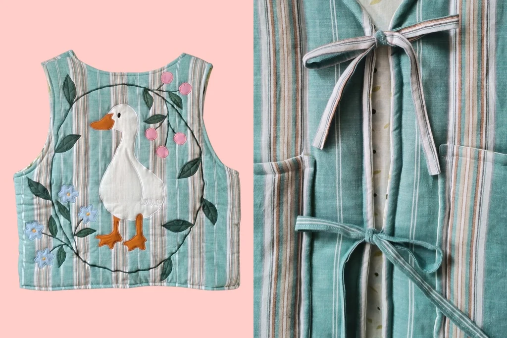 Pomysły na prezent świąteczny od polskich marek. Fot. patchpatch.store.pl Bawełniana kamizelka w paski ozdobiona haftem przedstawiającym białą gęś wśród różowych i niebieskich kwiatów oraz zielonych liści, zawiązywana z przodu na kokardki.