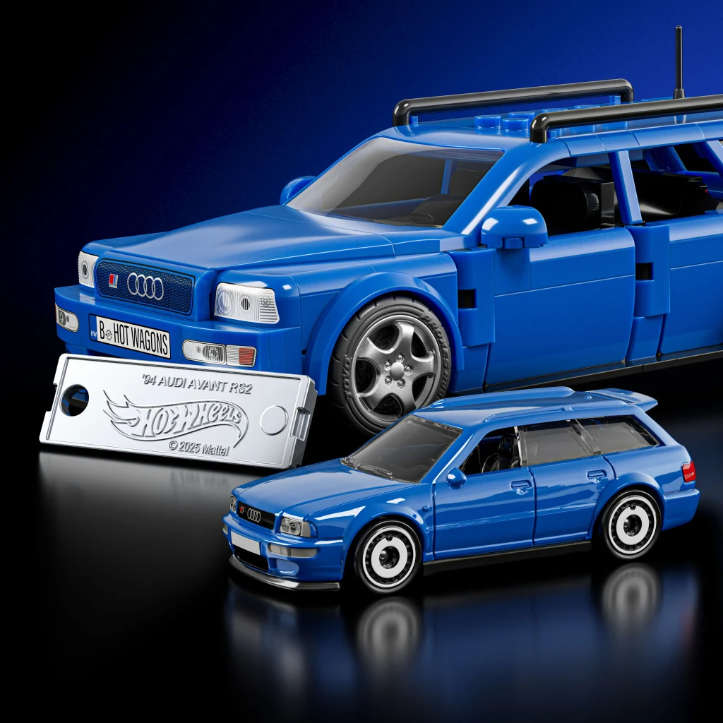 Audi Avant RS2 z serii Mattel Brick Shop Niebieski model samochodu Audi Avant RS2 wykonany z klocków, obok znajduje się metalowy model tej samej wersji auta, a także srebrna płytka z logiem Hot Wheels i nazwą modelu, wszystko na niebieskim tle.