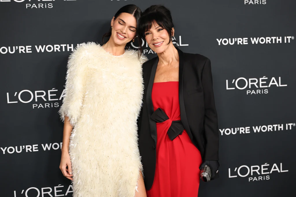 Kendall Jenner i Kris Jenner wyglądały bardziej jak siostry, niż jak matka i córka Dwie elegancko ubrane kobiety pozują razem na tle ścianki reklamowej L'Oréal Paris podczas oficjalnego wydarzenia. Jedna z nich ma na sobie jasną sukienkę z puszystego materiału, druga czerwoną suknię z czarną marynarką i satynową kokardą.