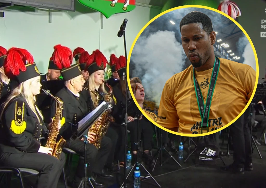 Wilfredo Leon był ważną postacią meczu Bogdanka LUK Lublin - Energa Trefl Gdańsk Górnicza orkiestra dęta w czarnych mundurach z czerwonymi pióropuszami na czapkach gra na instrumentach dętych podczas występu. W żółtym otoku widoczny sportowiec w żółtej koszulce z medalem na szyi, za nim unosi się dym.