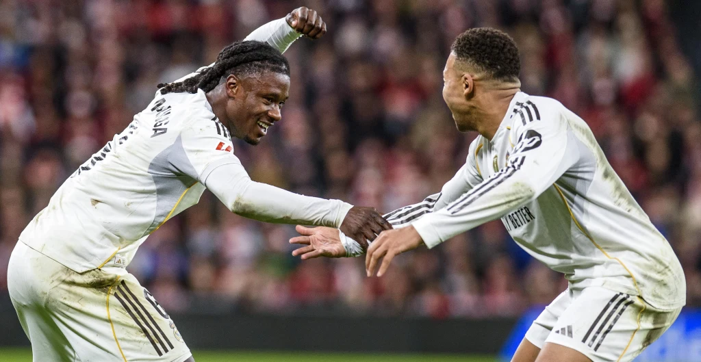 Eduardo Camavinga (z lewej) i Kylian Mbappe na San Mames nie szukali długo powodów do radości Dwóch piłkarzy w białych strojach celebruje sukces na murawie, uśmiechając się i łapiąc za ręce w dynamicznej pozie, w tle rozmyty tłum kibiców.