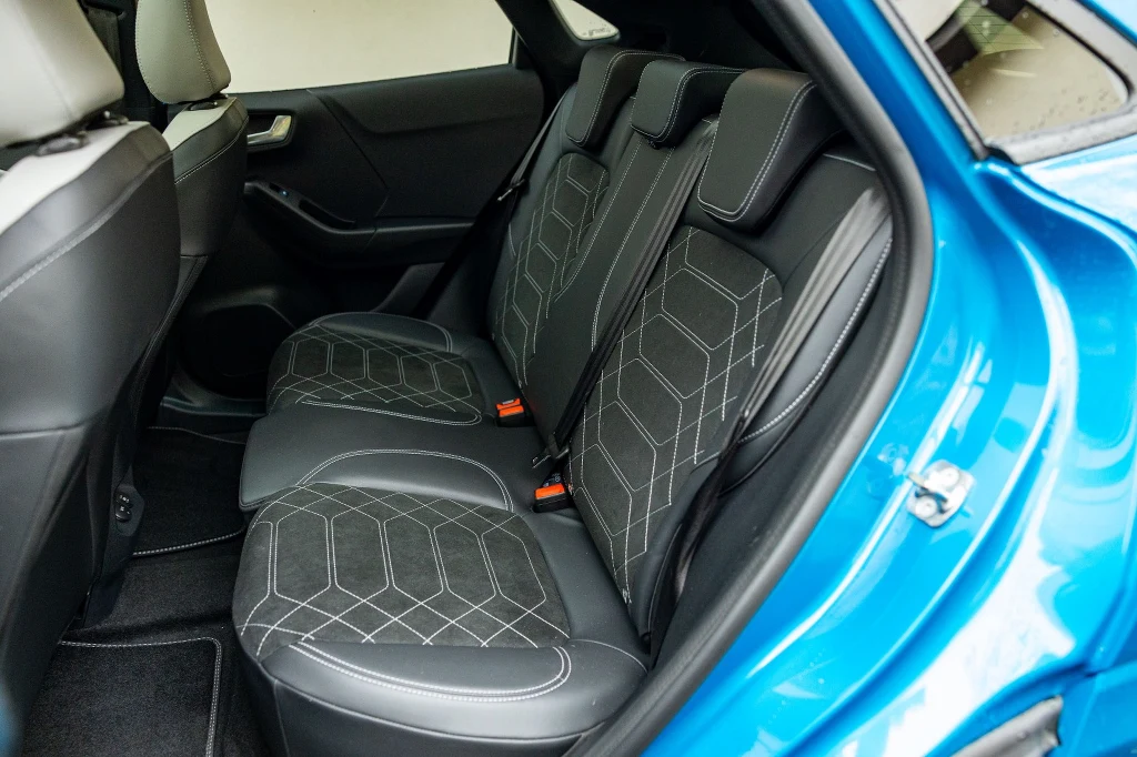 Na tylnej kanapie dorosłym będzie ciasno. Co gorsza, siedzi się z mocno uniesionymi kolanami Wnętrze samochodu z widokiem na tylne siedzenia wykończone czarną tapicerką z jasnymi przeszyciami, nowoczesny design, zagłówki dla pasażerów oraz wyraźnie widoczne uchwyty ISOFIX.